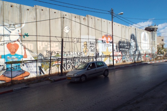 A car drives past the wall in Bethlehem (Beit Lehem) after having crossed through the Israeli military checkpoint just up the road. Photo credit: N. Ray/EAPPI